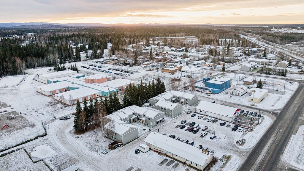A small town with buildings and cars is surrounded by snow.