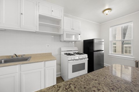 A kitchen with white cabinets and a granite countertop at Pleasant Oak Apartments, Oak Park, IL, 60302