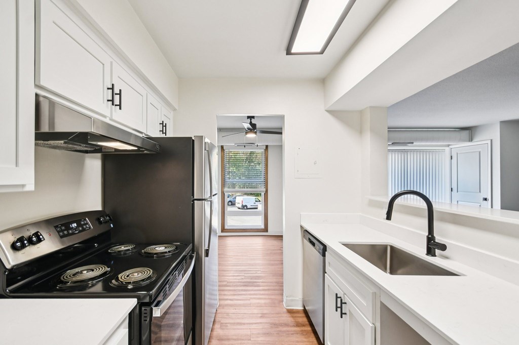 A kitchen with black appliances and white cabinets.