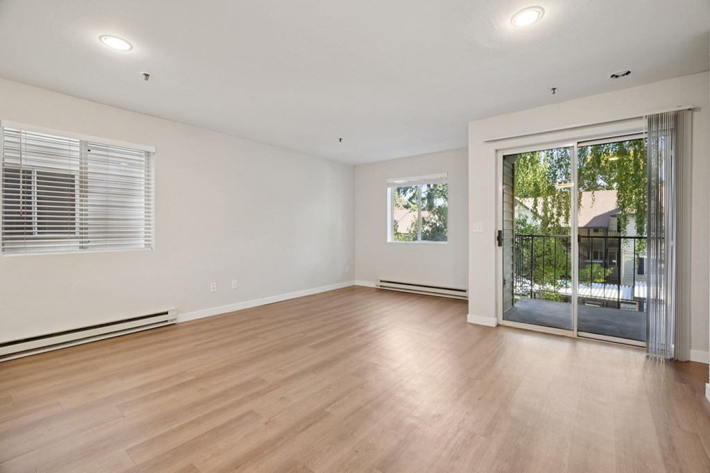 A room with wooden floors and a sliding glass door leading outside.