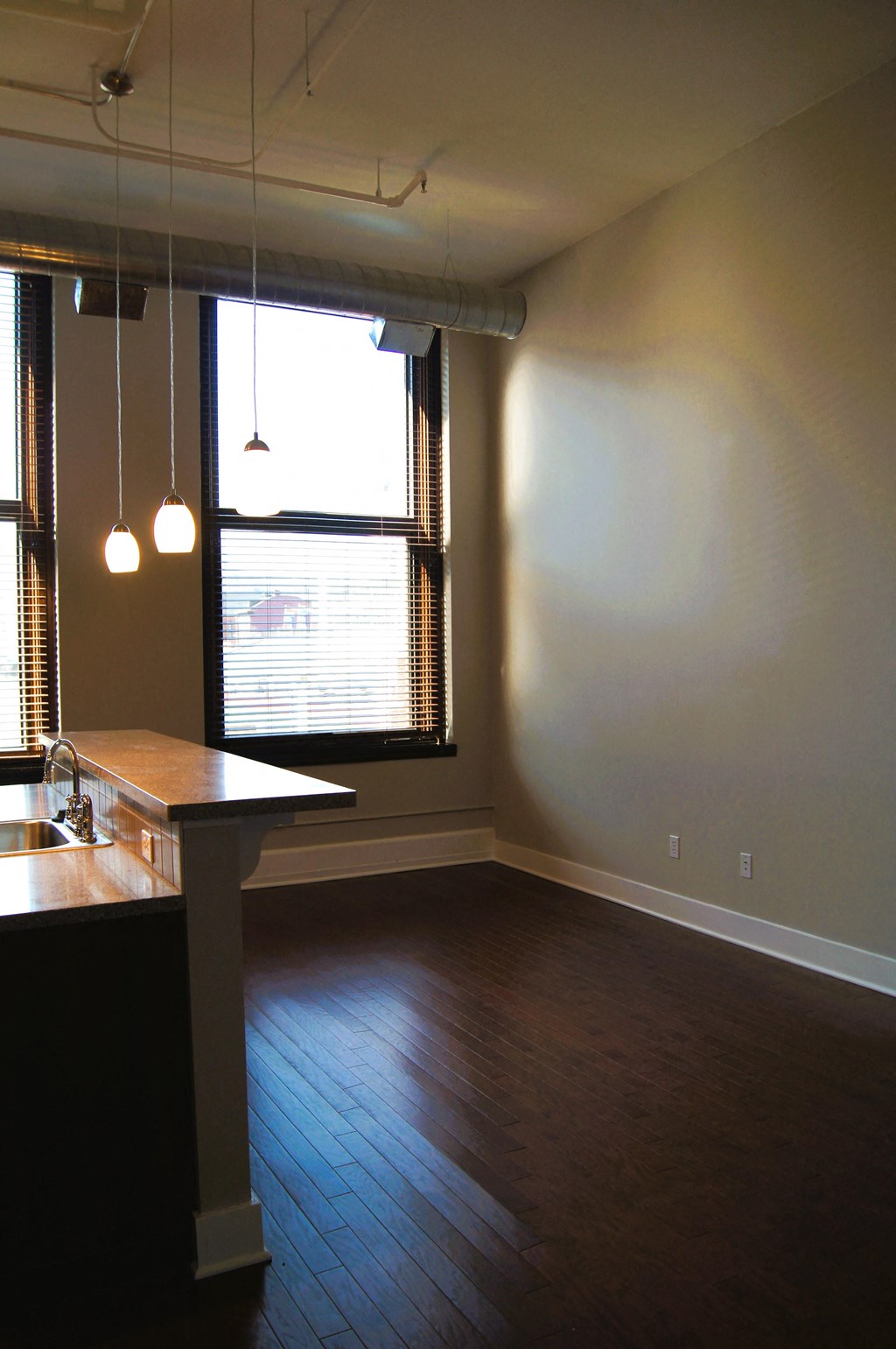 an empty living room with a kitchen and a window