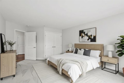 A bedroom with a large bed, a wooden nightstand, and a painting on the wall.