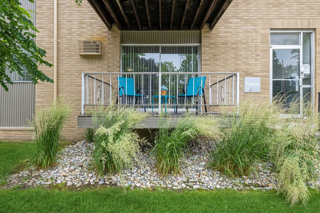 two blue chairs on a balcony in front of a brick building
