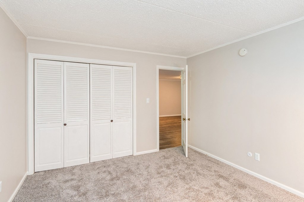 A room with a white door and a carpeted floor.