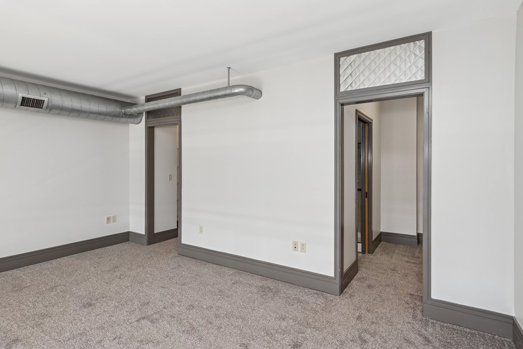 A room with a carpeted floor and a doorway leading to another room.