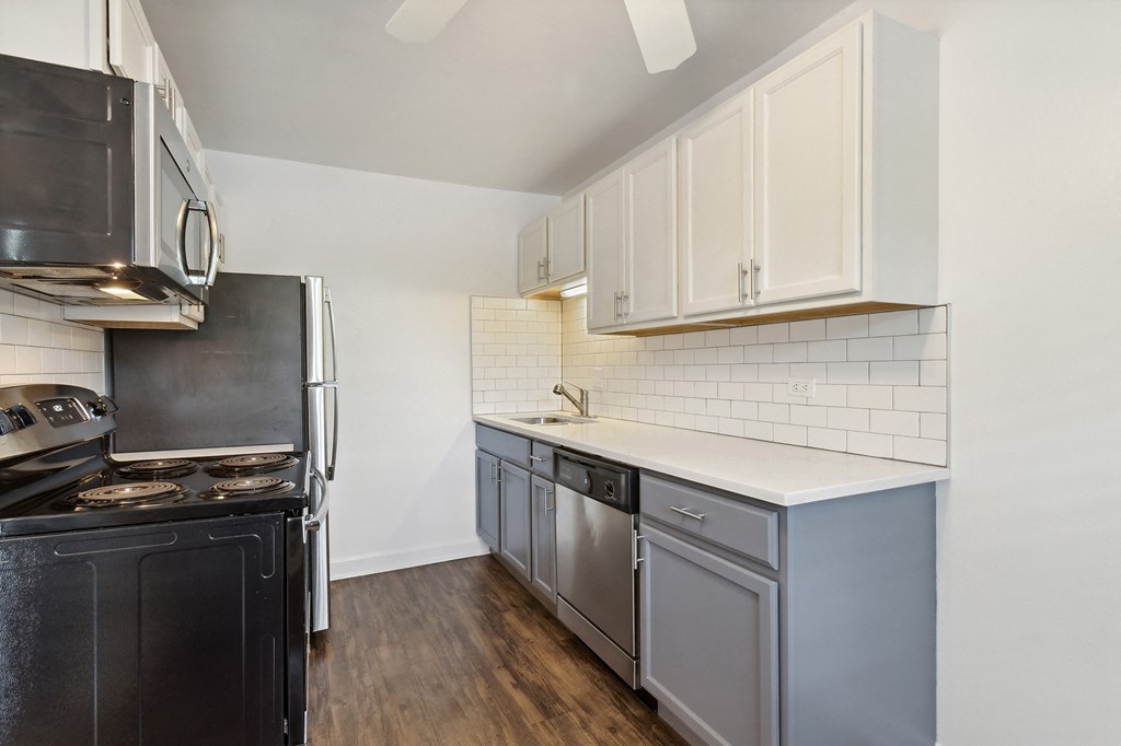 a kitchen with white cabinets and black appliances at The Hinsdale, Hinsdale, Illinois