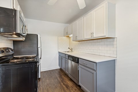 a kitchen with white cabinets and black appliances