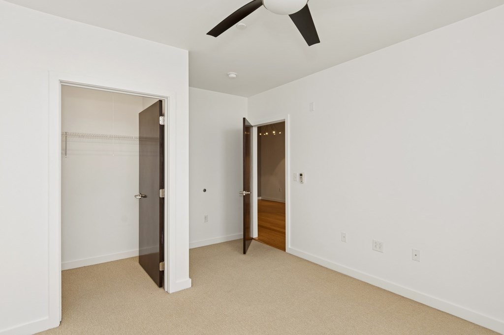 A room with a ceiling fan and two doors.