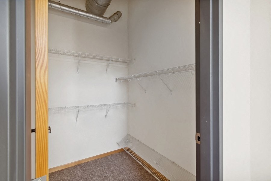 the closet in  bedroom with white walls and a wooden door