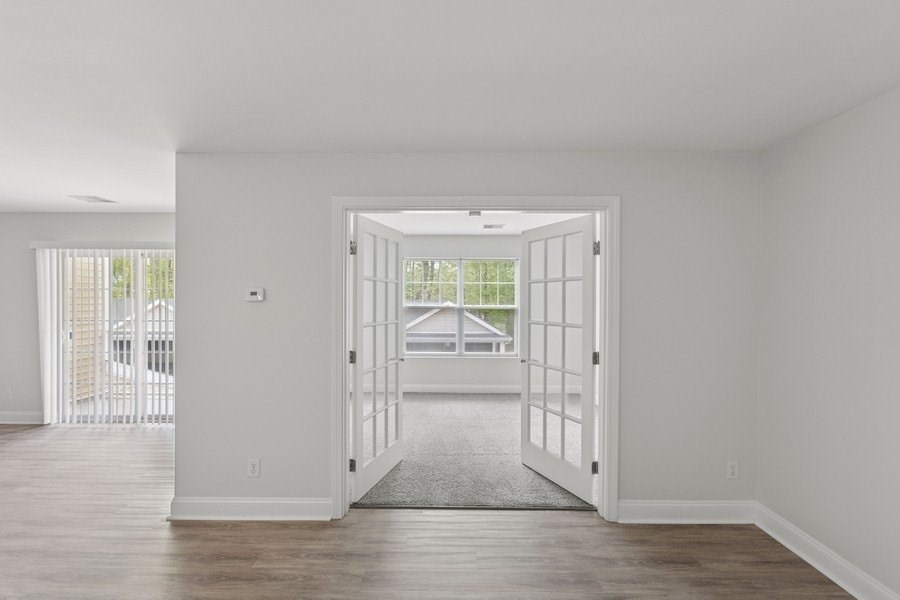 A room with a white door and a grey carpet.