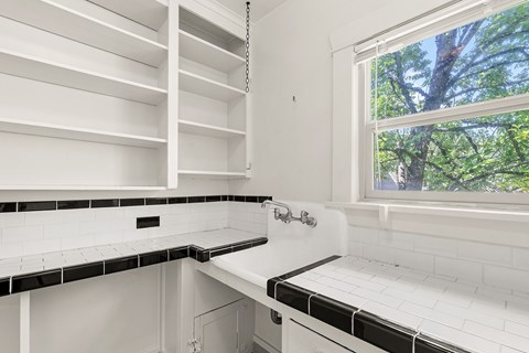 A white kitchen with black and white tiles.