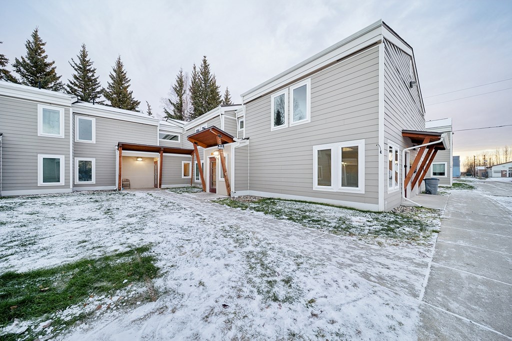 A modern house with a grey exterior and a brown roof.