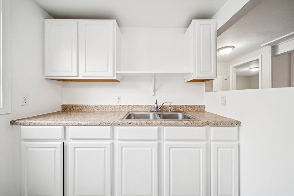 A kitchen with white cabinets and a granite countertop.
