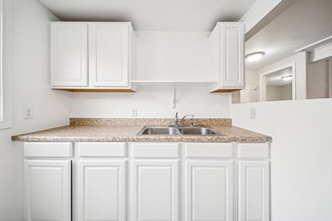 A kitchen with white cabinets and a granite countertop.
