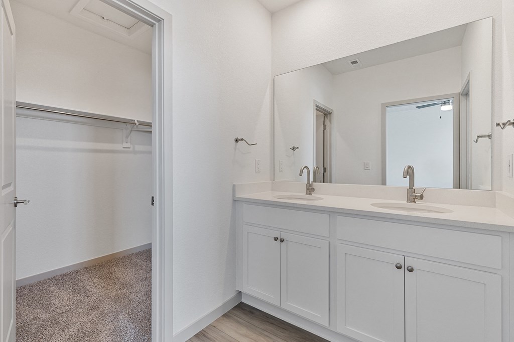 a luxurious bathroom with white cabinets and a mirror