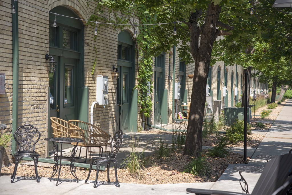 A tree stands next to a bench in front of a building.