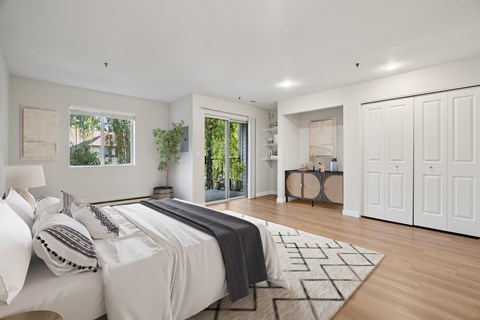 A bedroom with a large bed and a view of trees through the window.