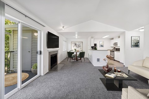 A modern living room with a grey carpet and white walls.