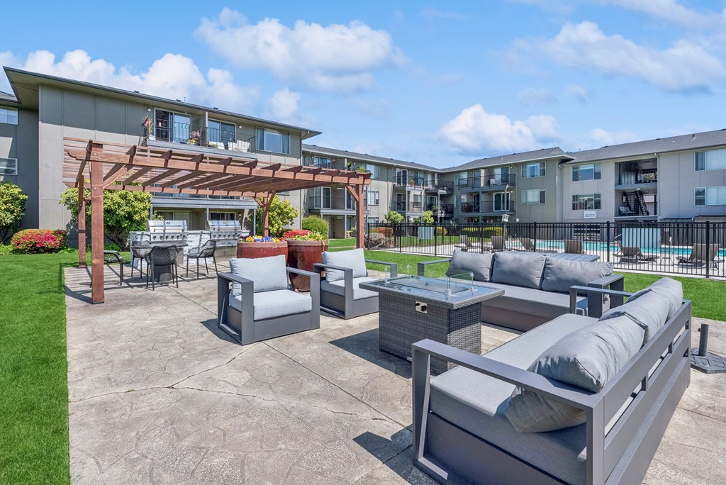 A patio area with grey furniture and a pool in the background.