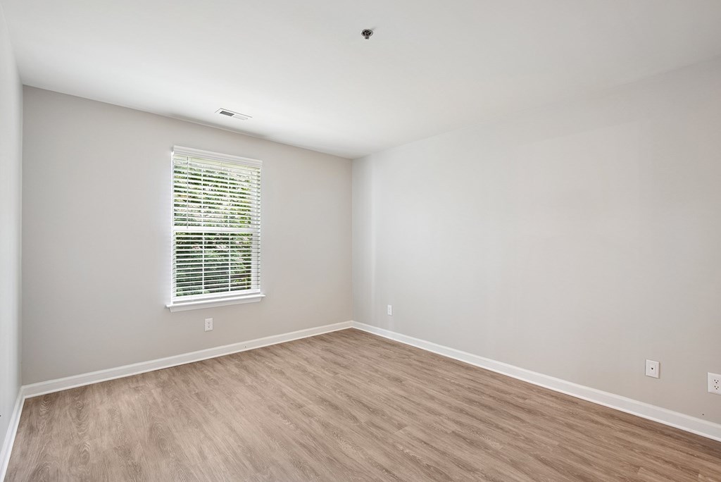 A room with a window and wooden flooring.