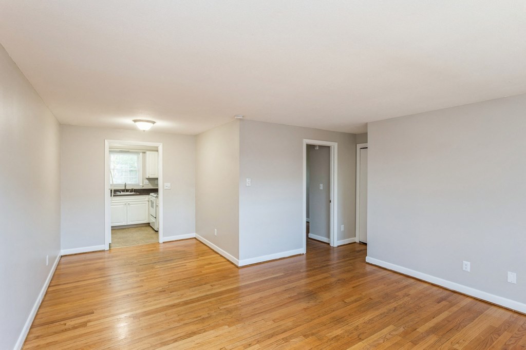 an empty living room with wood floors and white walls