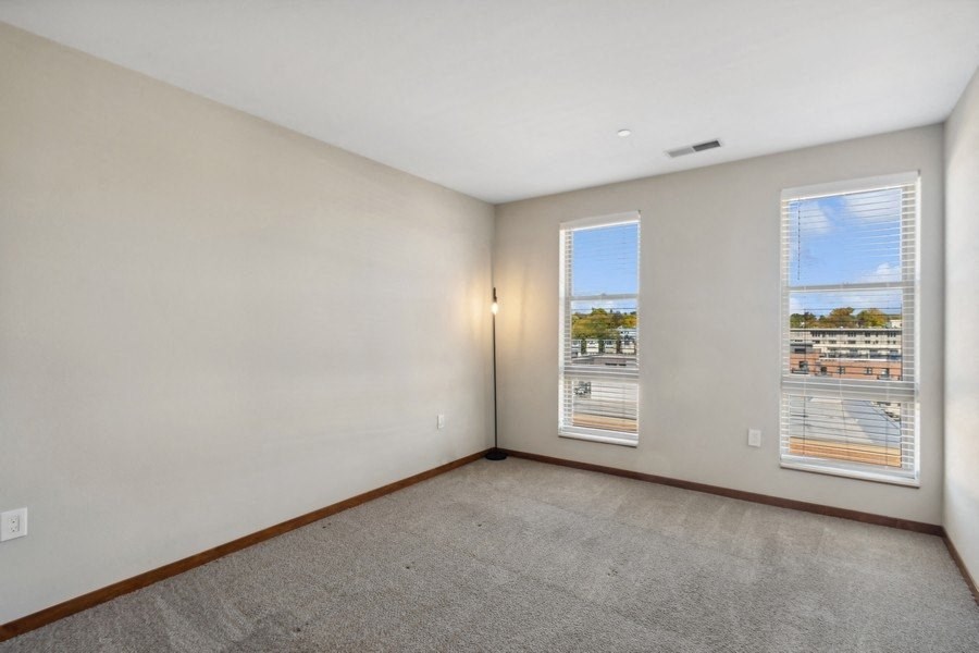 the living room of an apartment with two windows and a carpet