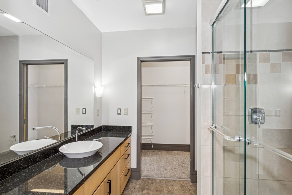 A bathroom with a sink, mirror, and shower.