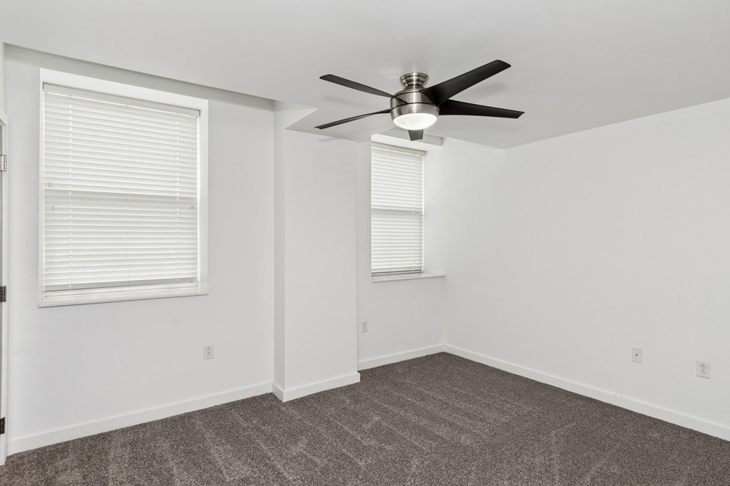 A room with a ceiling fan and carpeted floor.