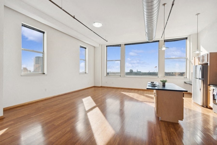 an empty living room with a kitchen and a large window