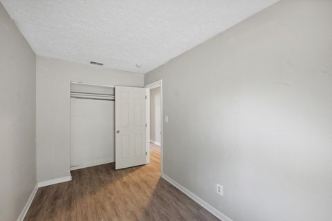 the living room of an apartment with white walls and wood flooring