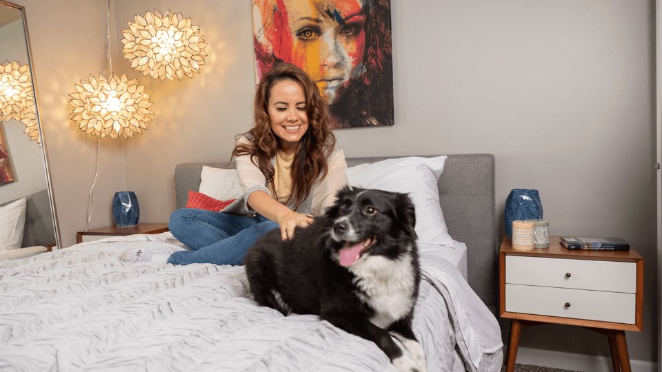 a woman sitting on a bed with a black and white dog at The View Apartments St Charles, Illinois, 60174