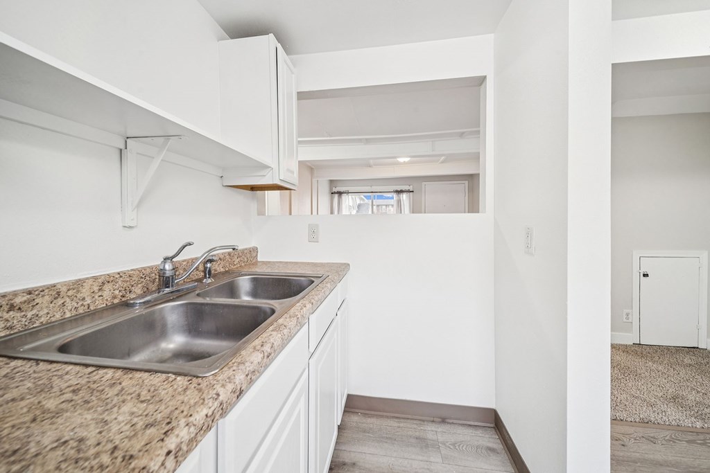 A kitchen with a granite countertop and white cabinets.