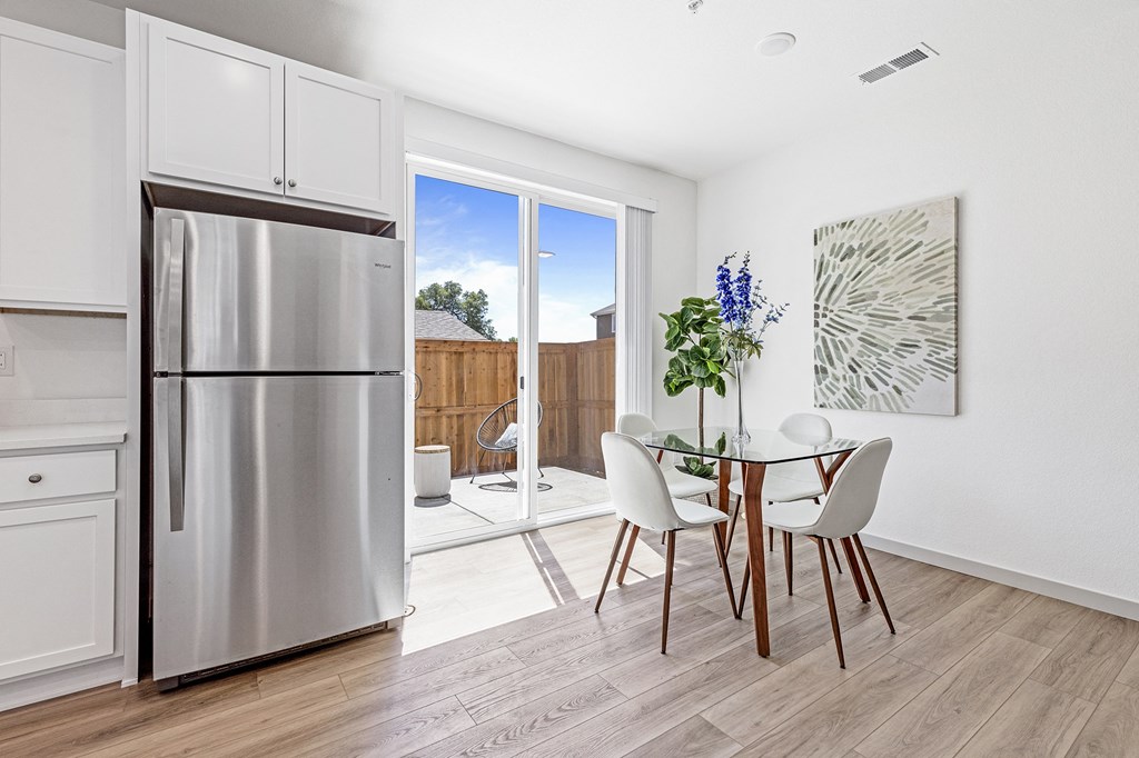 a kitchen with a stainless steel refrigerator and a table and chairs