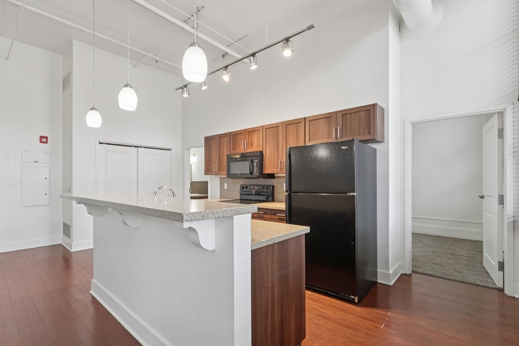 A kitchen with a black refrigerator and wooden cabinets.