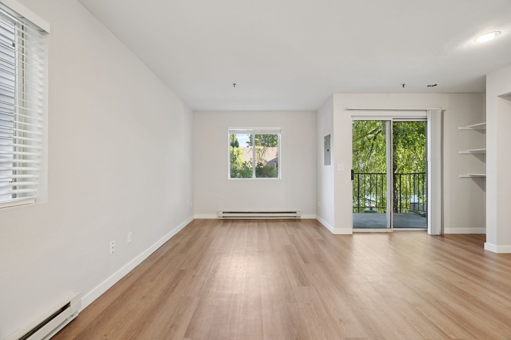 A room with wooden floors and a window with blinds.