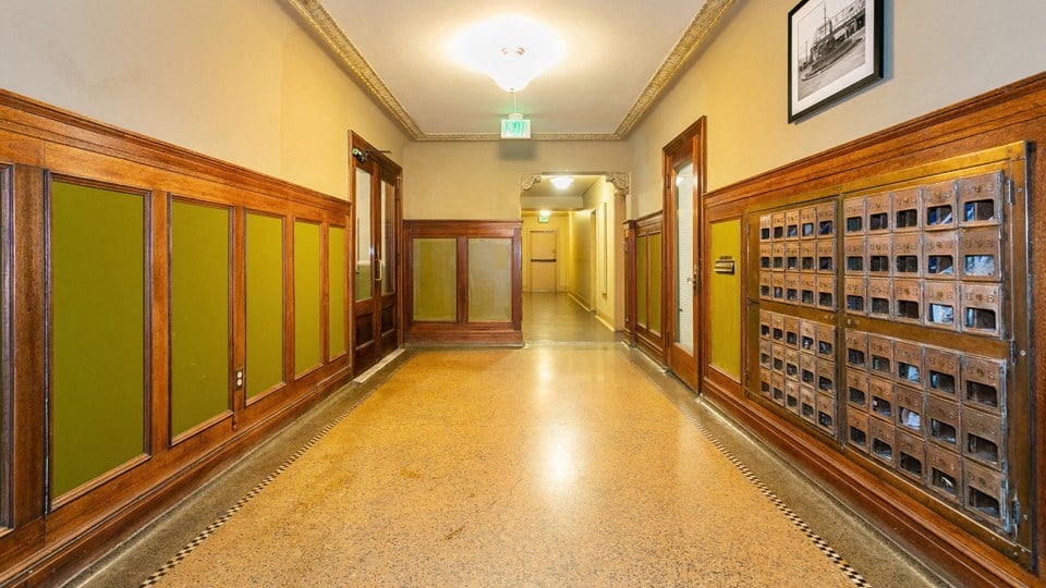 a hallway in a building with wooden doors and a tile floor