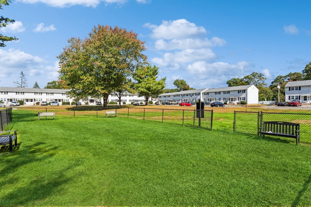 a dog park with benches and a fence in front of a building at Fox Hill Commons, Connecticut
