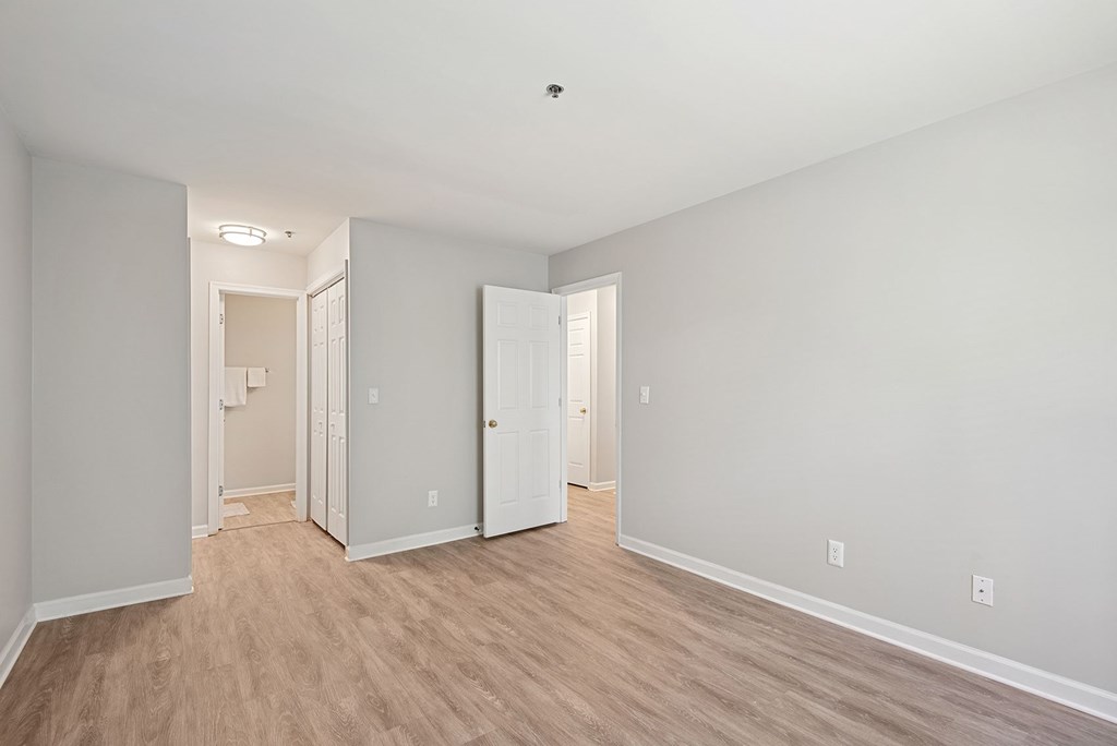 A room with white walls and wooden flooring with two doors.
