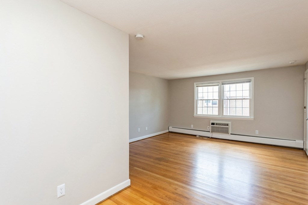 the living room of an empty house with wood floors and a window