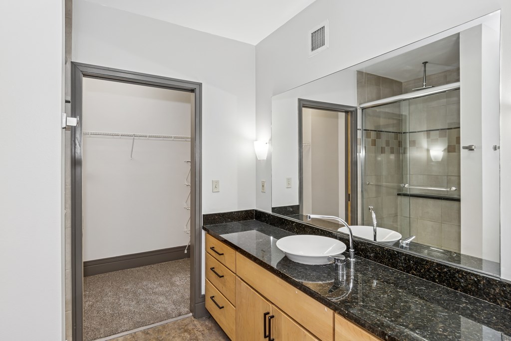 A bathroom with a sink, mirror, and a shower.