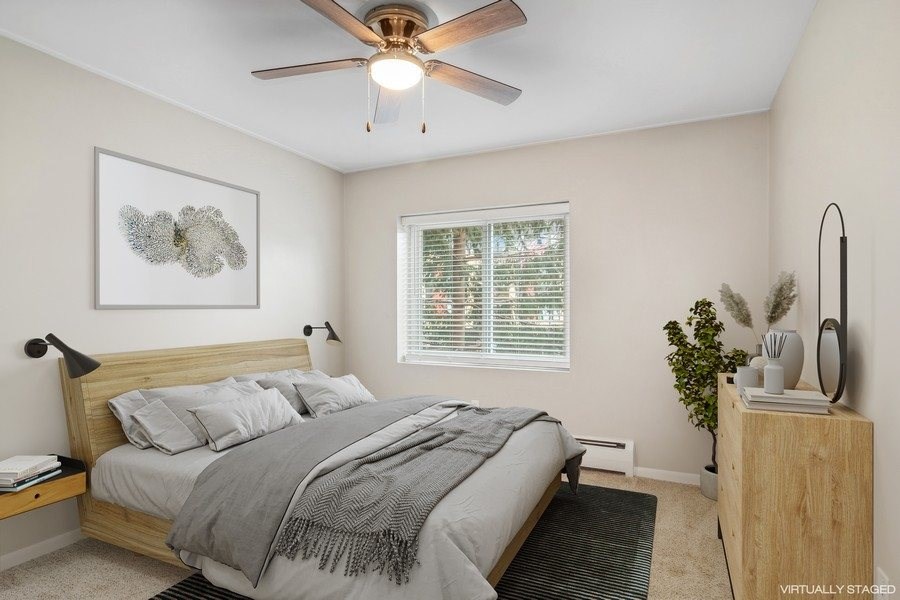 A bedroom with a bed, a ceiling fan, and a nightstand.