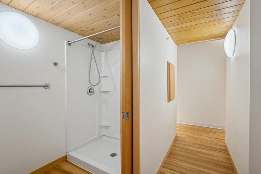A bathroom with a wooden ceiling and a white shower.