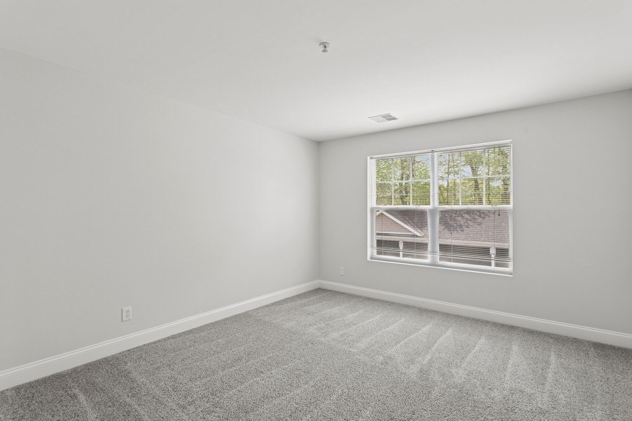 A room with a carpeted floor and a window showing a house and trees outside.