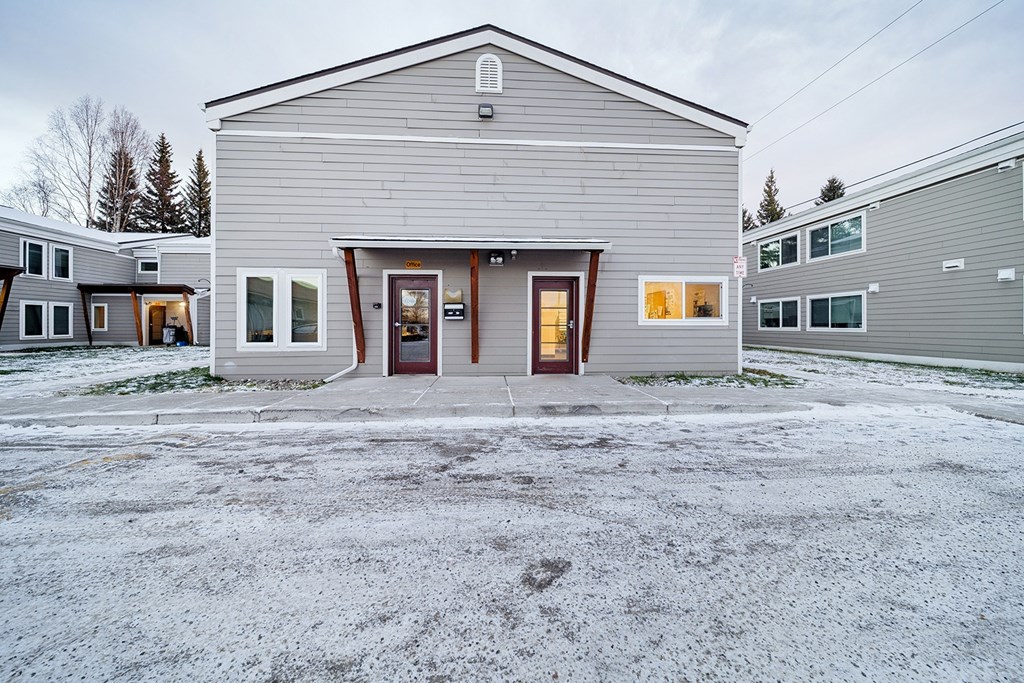 A grey building with a brown door and windows.