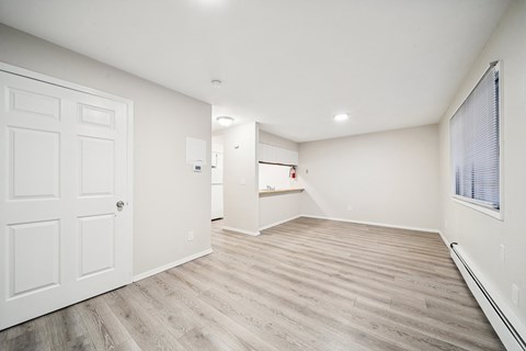A room with a white door and wooden flooring.