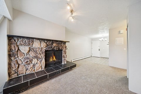 A stone fireplace with a fire going in it.