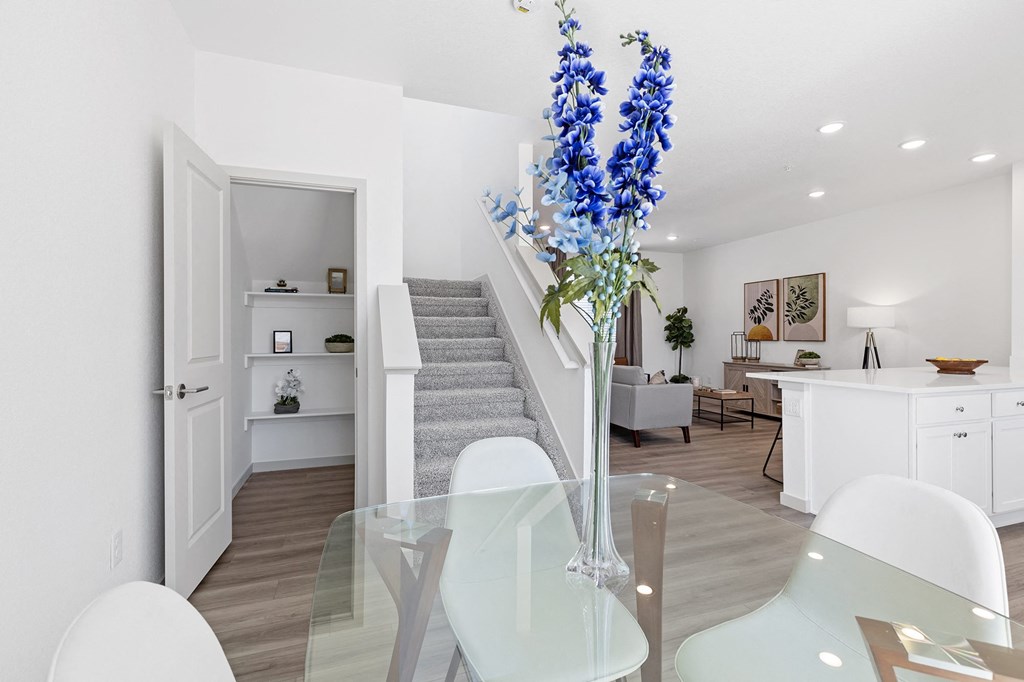 a living room and dining room with a glass table and blue flowers