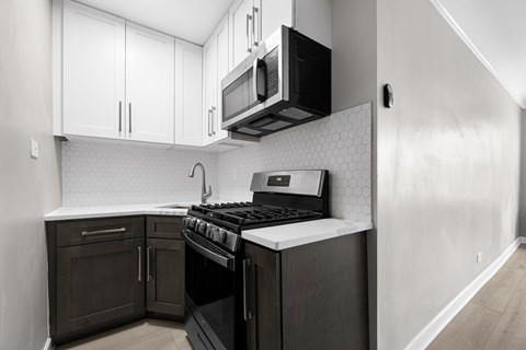 A kitchen with a black stove top oven and black microwave above it.