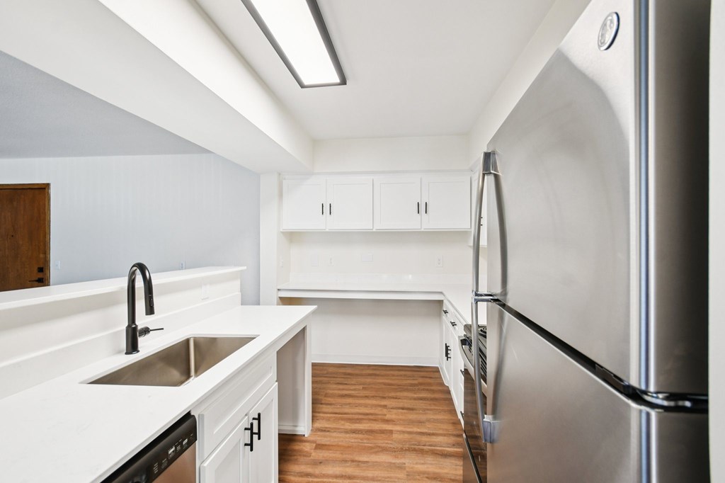 A modern kitchen with white cabinets and a stainless steel refrigerator.