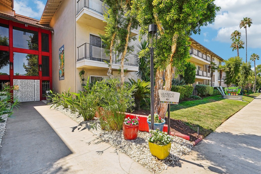 a sidewalk in front of a building with plants and trees